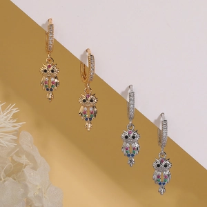 Orecchini a cerchio gufo color oro e argento con zirconi colorati su sfondo neutro