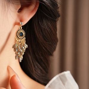 Close-up of bohemian tassel earrings with blue gemstone and beaded fringe on a model