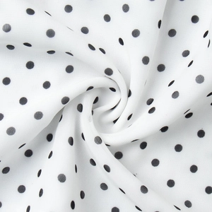 Detail view of lightweight white fabric with classic black polka dots and soft texture