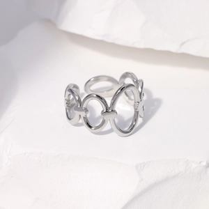 Macro detail of silver geometric cutout ring with heart patterns on stone surface