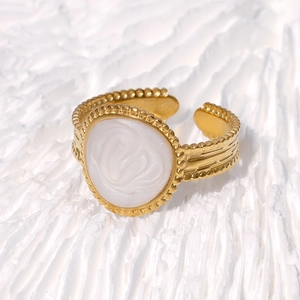 Bague ajustable rétro dorée avec relief ovale blanc sur fond texturé minimaliste