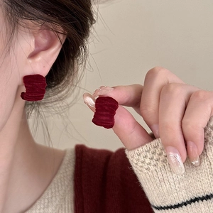 Close-up of burgundy flocked C-shaped earrings with vintage pleated texture for women