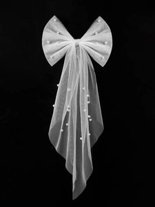 Detail shot of white mesh bow hair clip with pearls and pleated mesh on a dark background