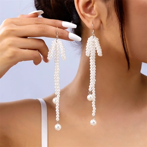 Detailed close-up of long pearl tassel earrings with delicate bow design worn by a model