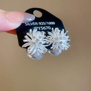 Detail of silver 925 flower earrings with pearl drop on black label card with price