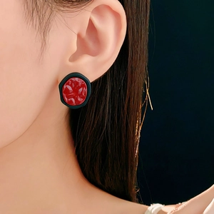 Gros plan détaillé de boucles d'oreilles géométriques rouges et noires en émail texturé