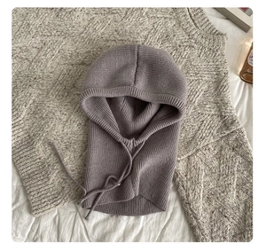 Detail of grey knitted balaclava with adjustable drawstring on soft textured fabric