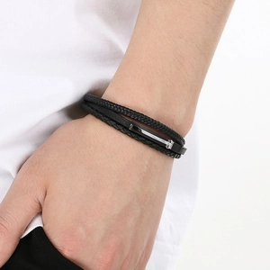 Detail of multi-layer woven black leather bracelet with silver magnetic buckle on wrist