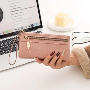 Detail of pink pebbled leather wallet with golden leaf zipper and detachable wrist strap