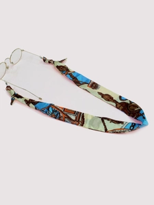 Detail of patterned silk eyewear strap with equestrian prints and gold round glasses