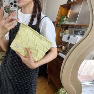 Dettaglio ravvicinato della borsa cosmetica gialla trapuntata con etichetta arcobaleno
