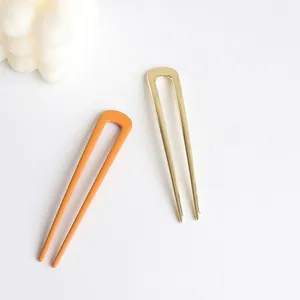 Minimalist U-shaped metal hairpins in gold and matte orange for elegant hair styling