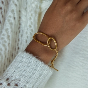 Detail of gold evil eye OT buckle bracelet on model with white knit sweater