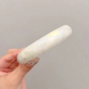 Detailed view of the pearlescent white shell spring hair clip with glossy texture