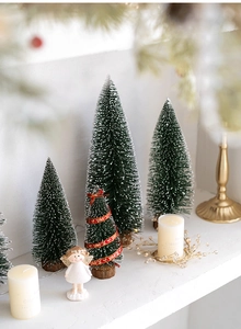 Close-up of green flocked mini Christmas trees and angel ornaments for tabletop decor