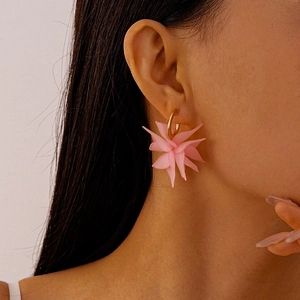 Close-up of pink layered acrylic flower earrings worn by a model in soft lighting