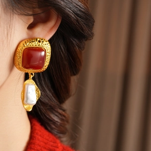 Close-up of vintage square red resin earrings with white baroque pearl on gold base