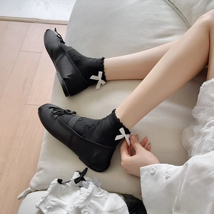 Detail of black JK ankle socks with ruffled edges and white ribbon bows on Mary Jane shoes