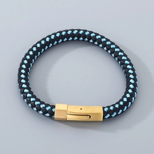 Detail of multi-layer black and blue woven leather bracelet with golden metal clasp