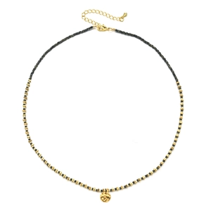 Macro detail of gold-plated hammered pendant with black beads and adjustable lobster clasp