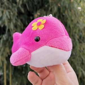 Cute pink plush whale keychain with a small yellow flower detail held in one hand