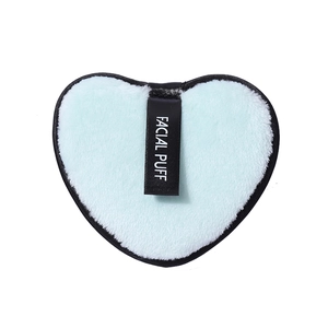 Blue heart-shaped microfiber facial puff with black ribbon trim and white label text