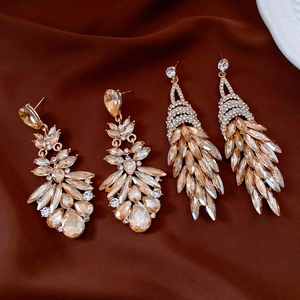 Macro shot of gold tassel drop earrings with sparkling crystals on dark satin fabric