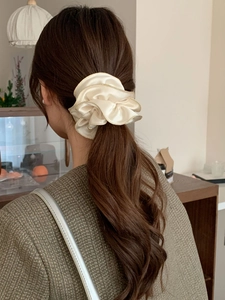 Détail d'un chouchou en satin crème élégant avec bord doré porté en queue de cheval
