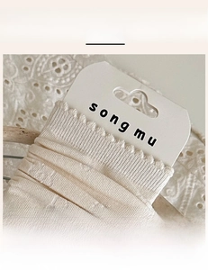 Macro shot of off-white socks with elastic ribbed cuffs and delicate wavy lace edges