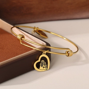 Detailed view of golden heart charm showing mother embracing child on adjustable bracelet