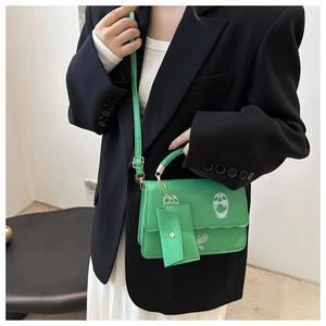 Detail of green skull print crossbody bag with detachable coin purse and gold hardware