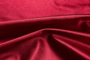Detailed view of dark red satin fabric with elegant drapes and smooth silky texture