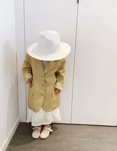 Dettaglio bambina con blazer giallo senape, abito in pizzo e cappello di paglia
