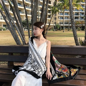 Detail of ethnic style beach shawl with colorful patterns worn over a white lace dress