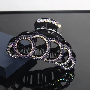 Classic black hair claw clip with sparkling purple and iridescent rhinestones in studio