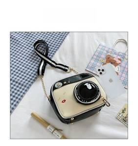 Detail view of a creative camera-shaped crossbody bag with wide striped shoulder strap