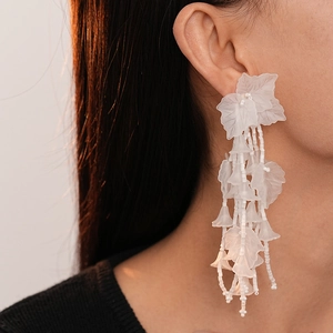 Detailed close-up of white acrylic leaf petal earrings with elegant beaded tassels
