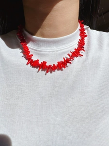 Close-up of a red branch-shaped coral-style necklace worn on a female model