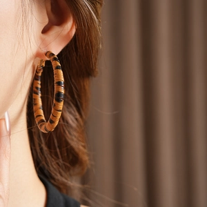 Gros plan de grandes boucles d'oreilles créoles à motif léopard avec une finition rayée