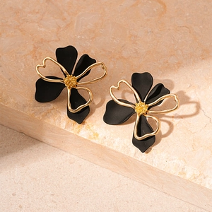 Macro view of matte black flower petal earrings with golden metallic outlines
