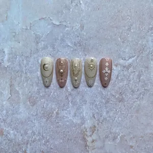 Elegant press-on nails with golden celestial sun, moon, and pearl charms on beige base