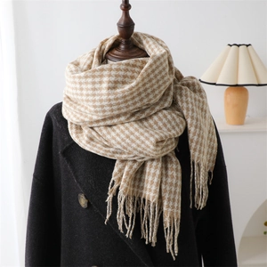 Classic beige houndstooth scarf with tassels on a mannequin in a black wool coat