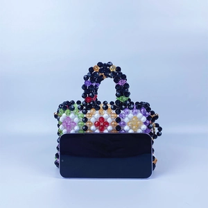 Detailed view of a handmade colorful beaded bag showing grid pattern and compact size