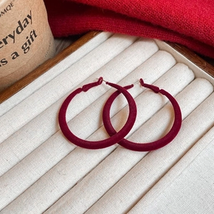 Detail view of red velvet hoop earrings on jewelry tray with elegant autumn atmosphere