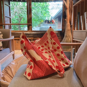 Gros plan d'un sac cabas en toile à pois rouges posé sur une chaise ensoleillée