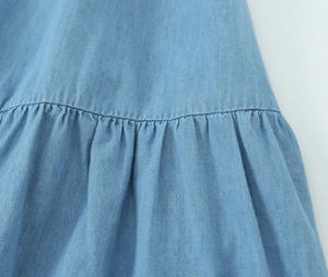Gros plan sur la texture du denim bleu clair avec coutures détaillées et plis soignés