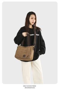 Detailed view of khaki canvas messenger bag featuring wide strap and leather logo detail