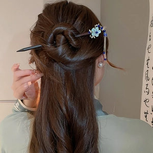 Detail of butterfly tassel hairpin with blue flowers and silver leaves in bun