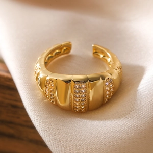 Macro detail of 18K gold plated ring with micro-pave zircons on beige silk background