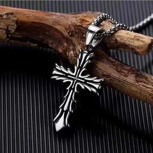 Vintage cross pendant necklace in silver titanium steel with leaf textures on wood background